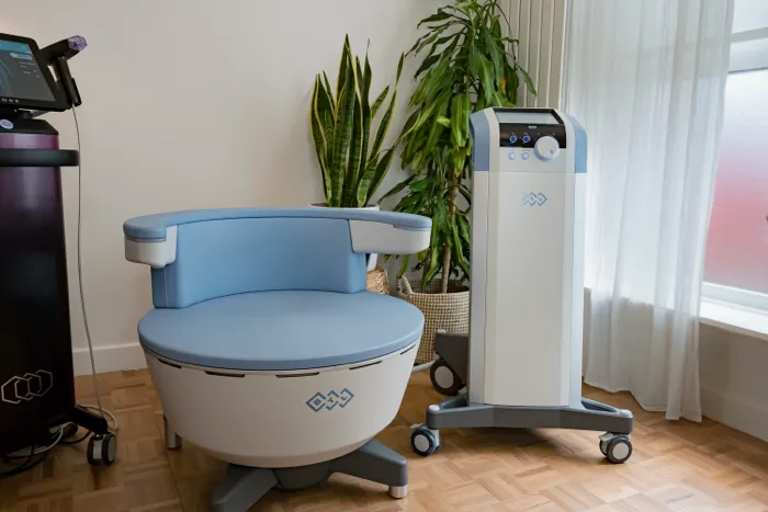 BTL Emsella chair for pelvic floor therapy inside Lift and Revive clinic, placed beside medical equipment and indoor plants.