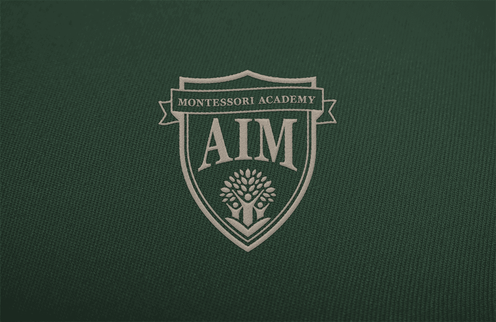 Embroided Crest for Aim Montessori Academy on green fabric