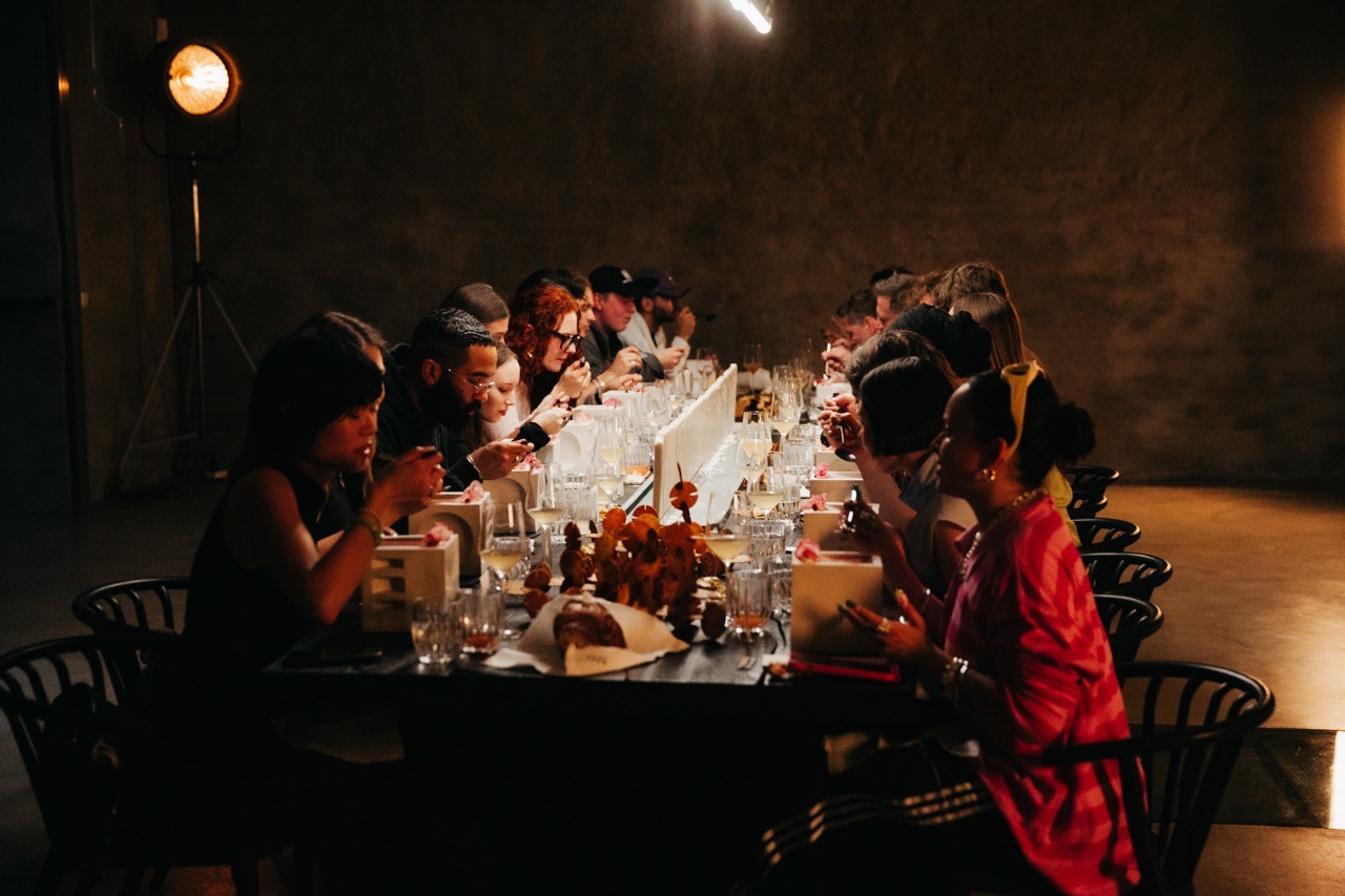 A laptop on the sand showing a person with a straw hat, surrounded by shells.
