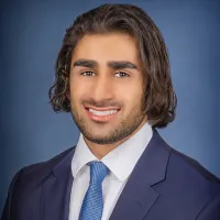 Amir Saran headshot in front of blue background