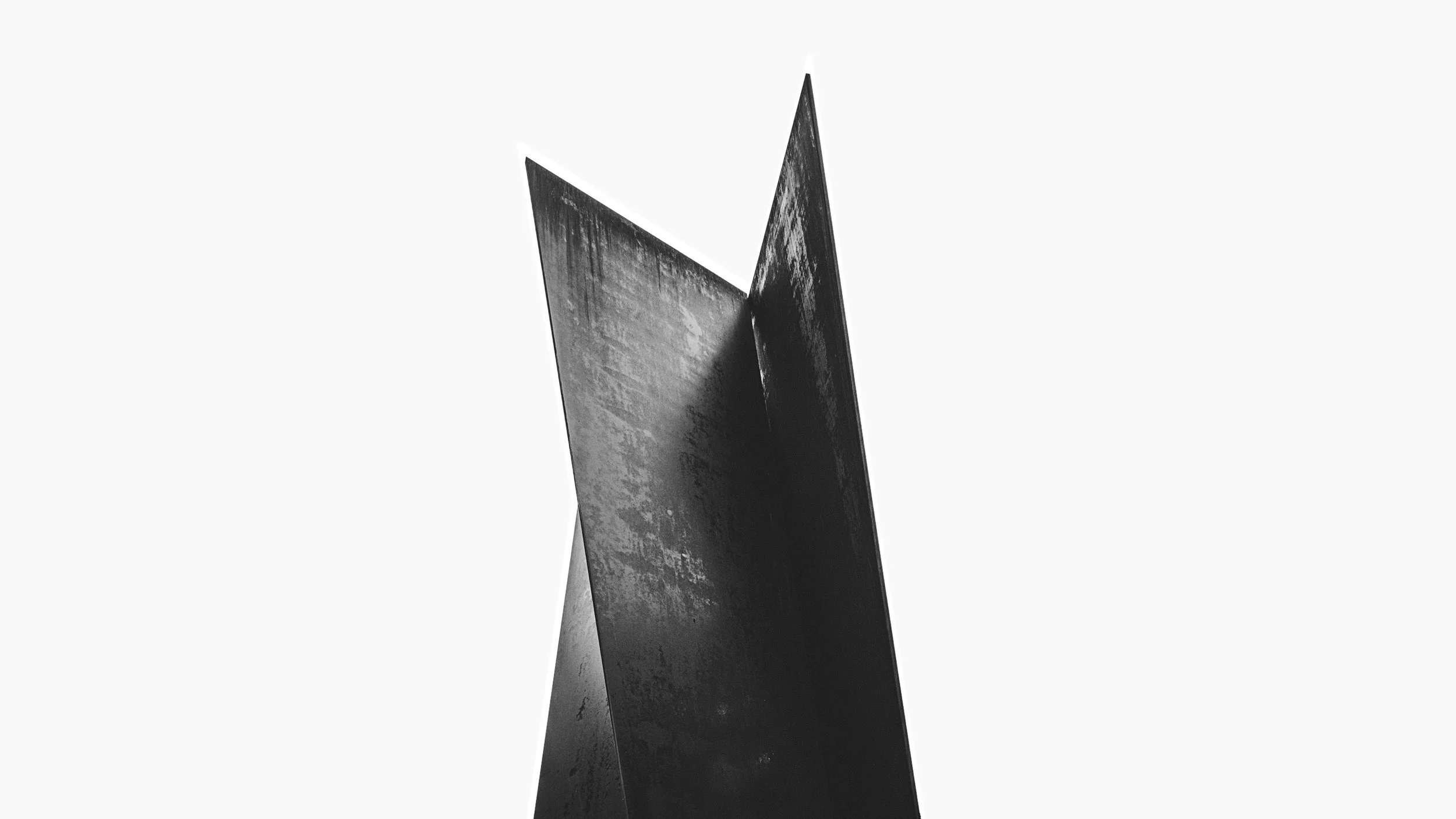 Richerd Serra – Abstract black shape with sharp edges against a light background, creating a minimalist and sculptural appearance.