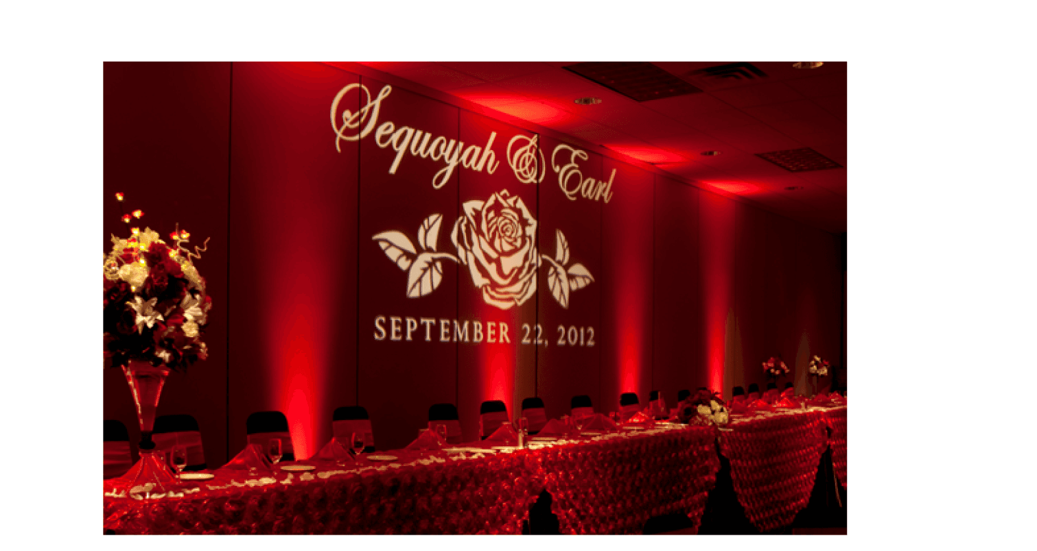 An elegant, custom light monogram projecting the bride and groom's names onto a decorative backdrop at their wedding reception