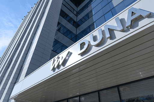  image of Imperial Dental's modern treatment room featuring blue dental equipment, a monitor with the clinic’s logo, and natural light from large windows overlooking a park.