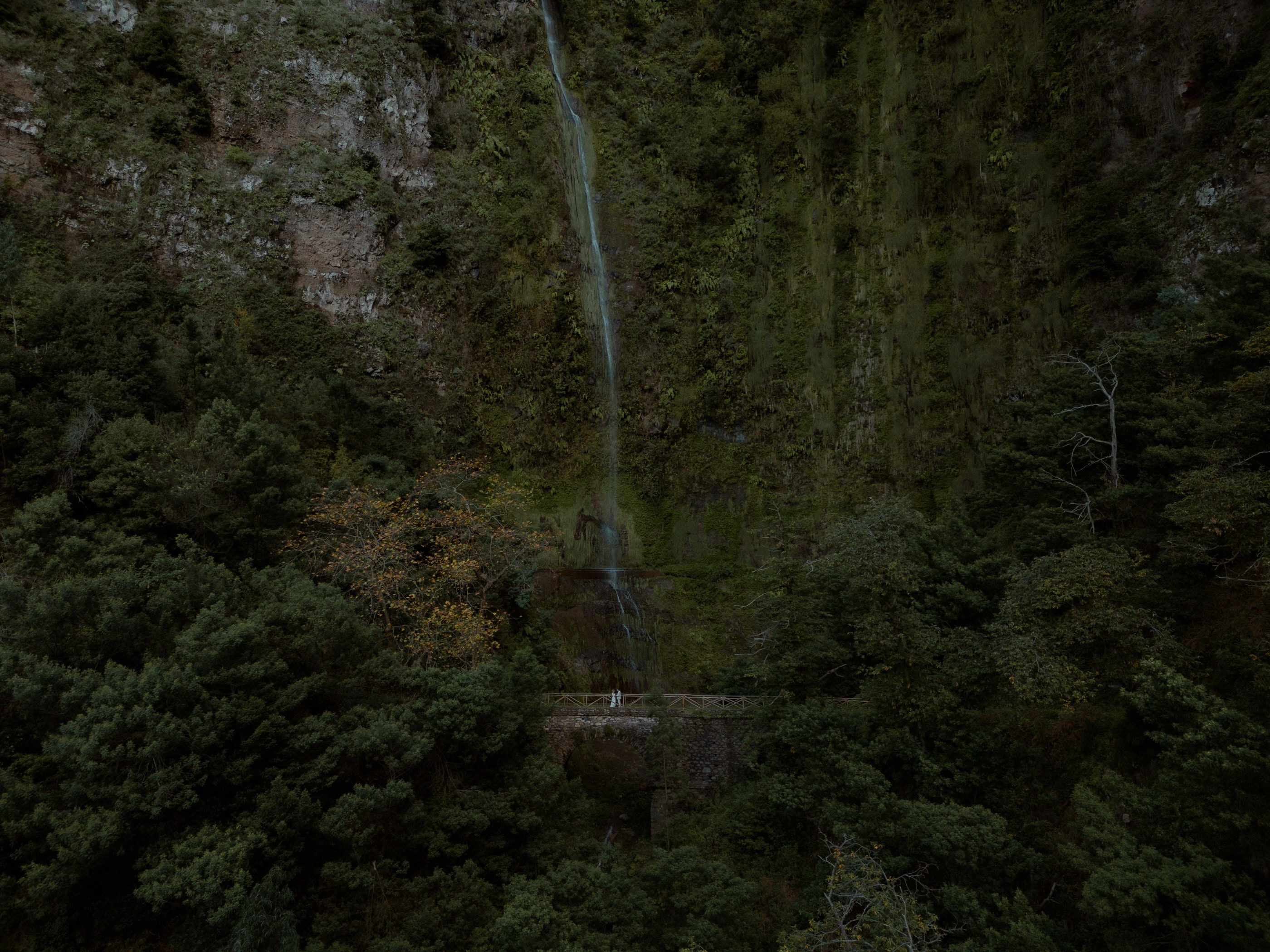 hidden green waterfall madeira with couple on bridge drone shot