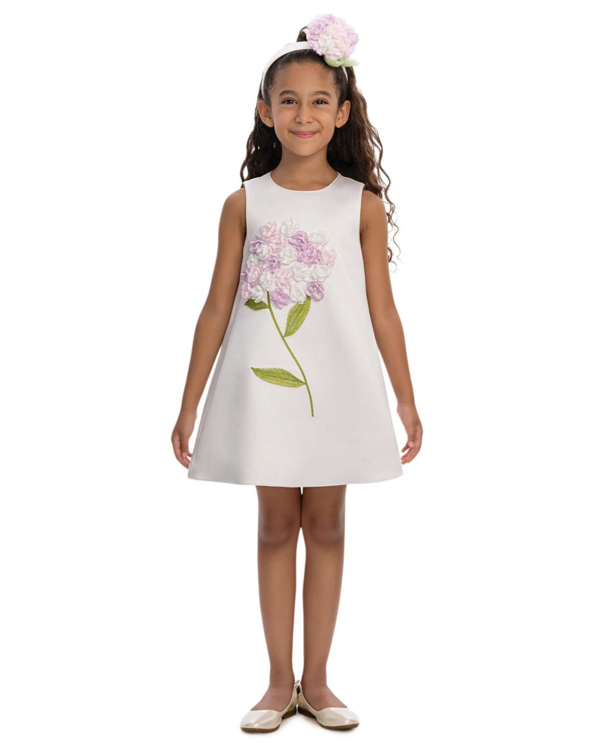 Young girl wearing a white dress with floral design on a white background
