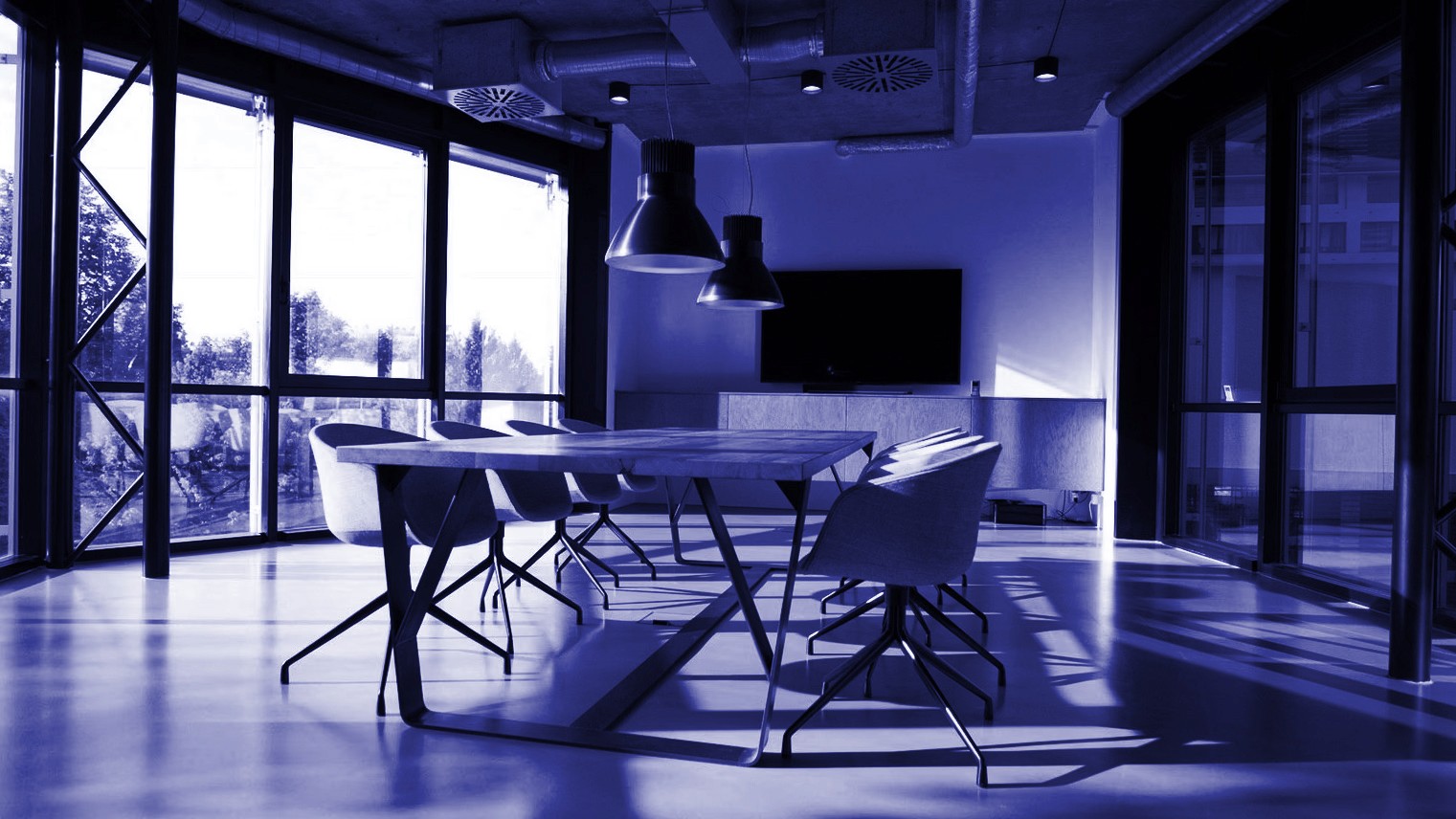 Büyük pencerelerden doğal ışık alan, pembe sandalyeli ve ahşap masalı modern bir toplantı odası.