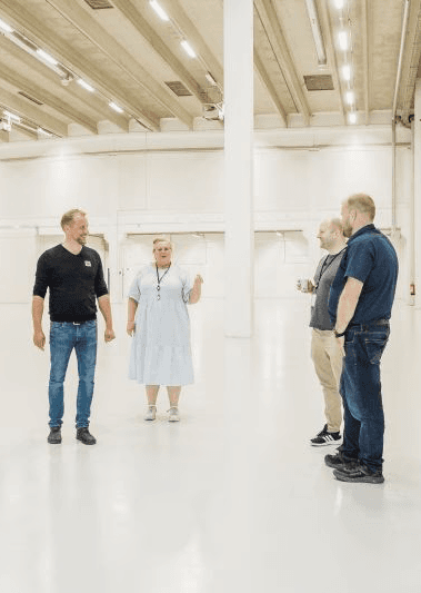 A smiling young man with crossed arms, wearing a plaid shirt and white t-shirt, poses against a dark background.