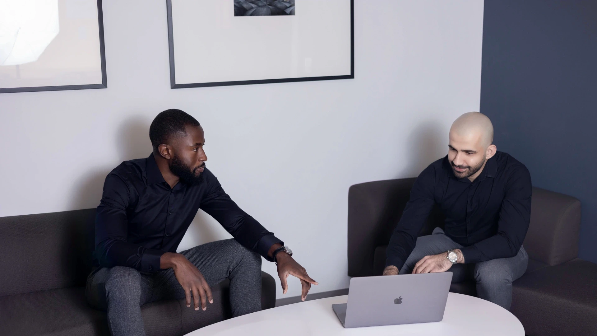 Black and white image of people working at a table with laptops, showing hands gesturing during discussion of digital content displayed on screens, with fabrica® logo in the corner.