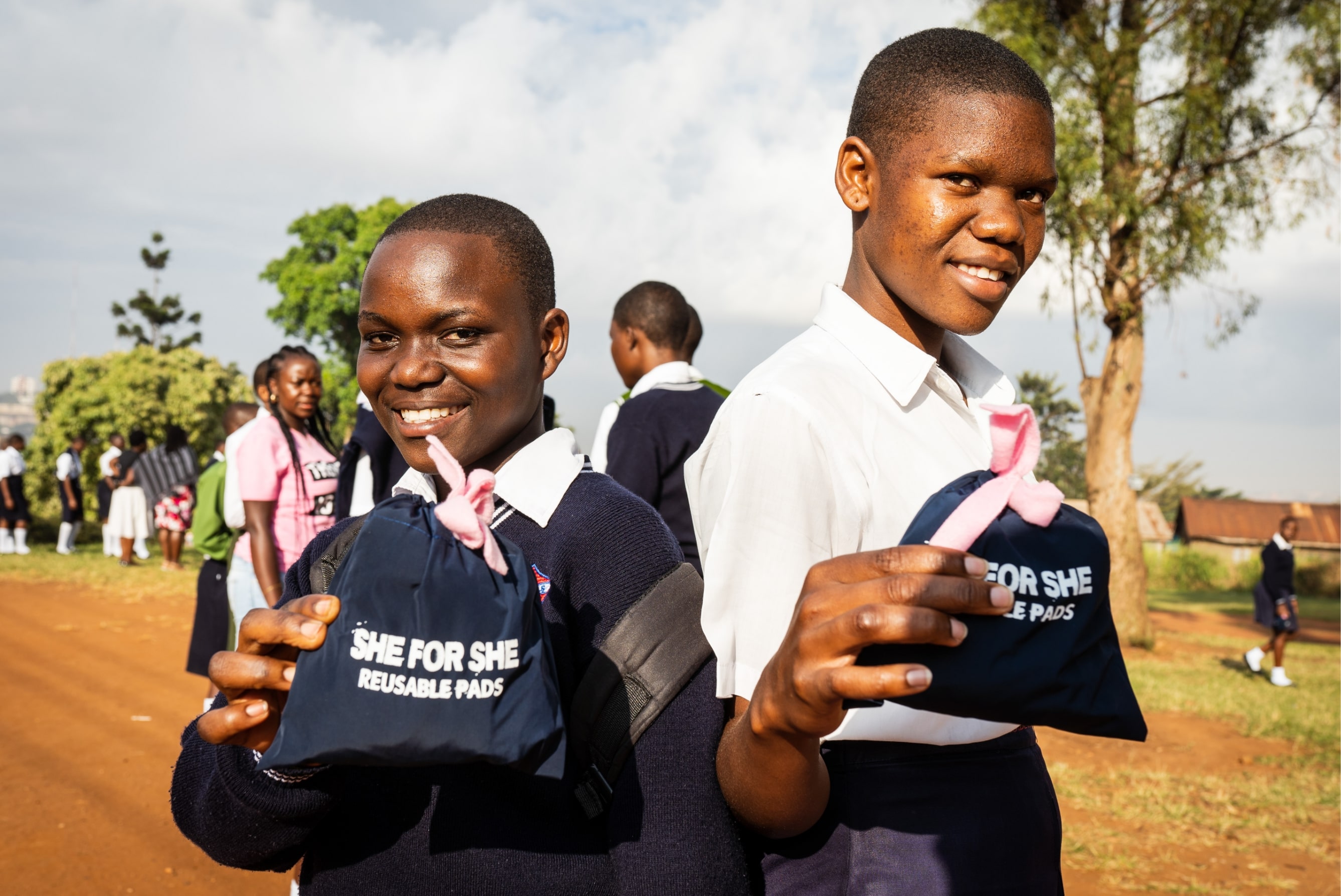 Peninah and her friend holding SHE FOR SHE menstrual pads.