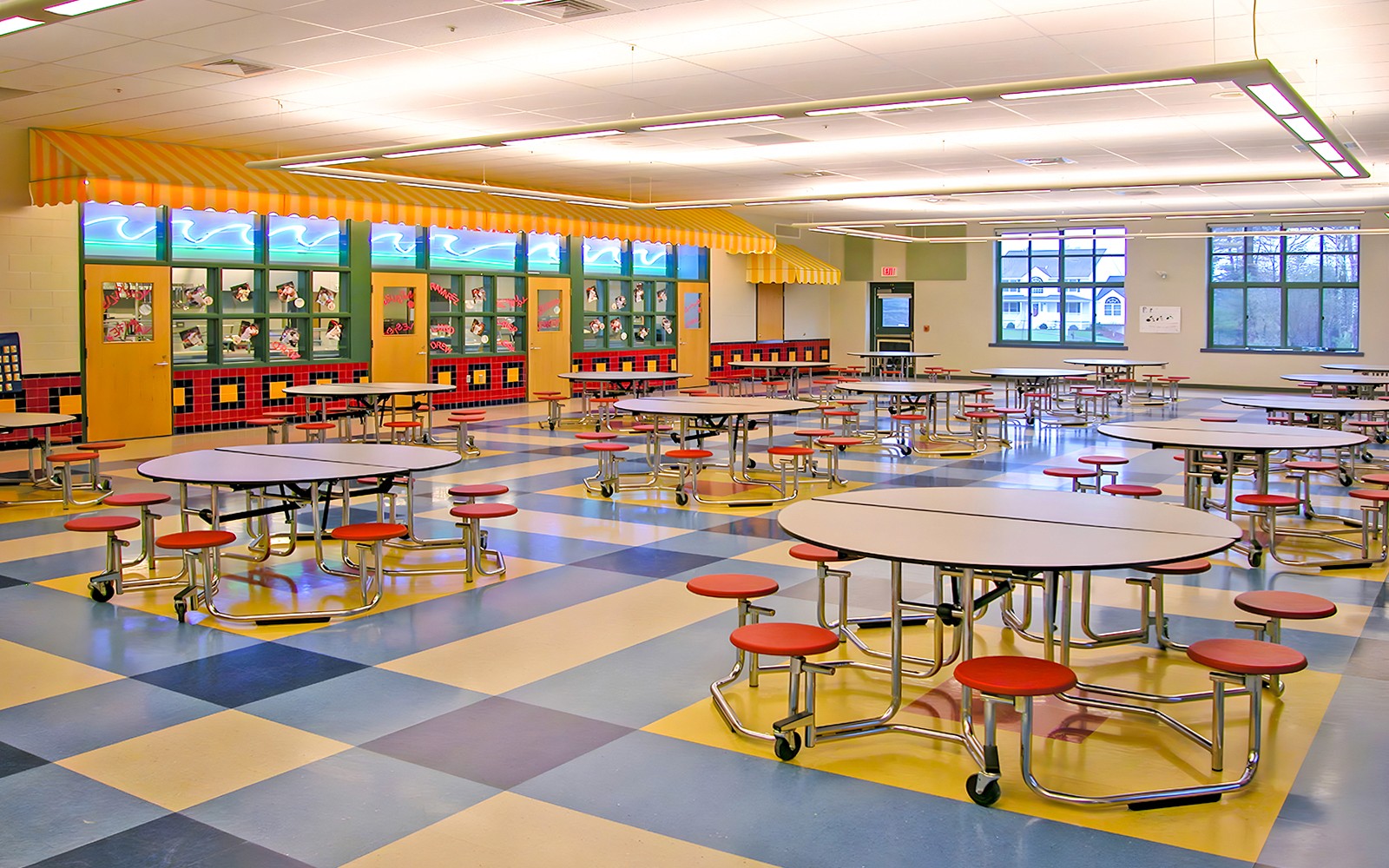 Colorful cafeteria with round tables and red stools at KidsSTOP Singapore.