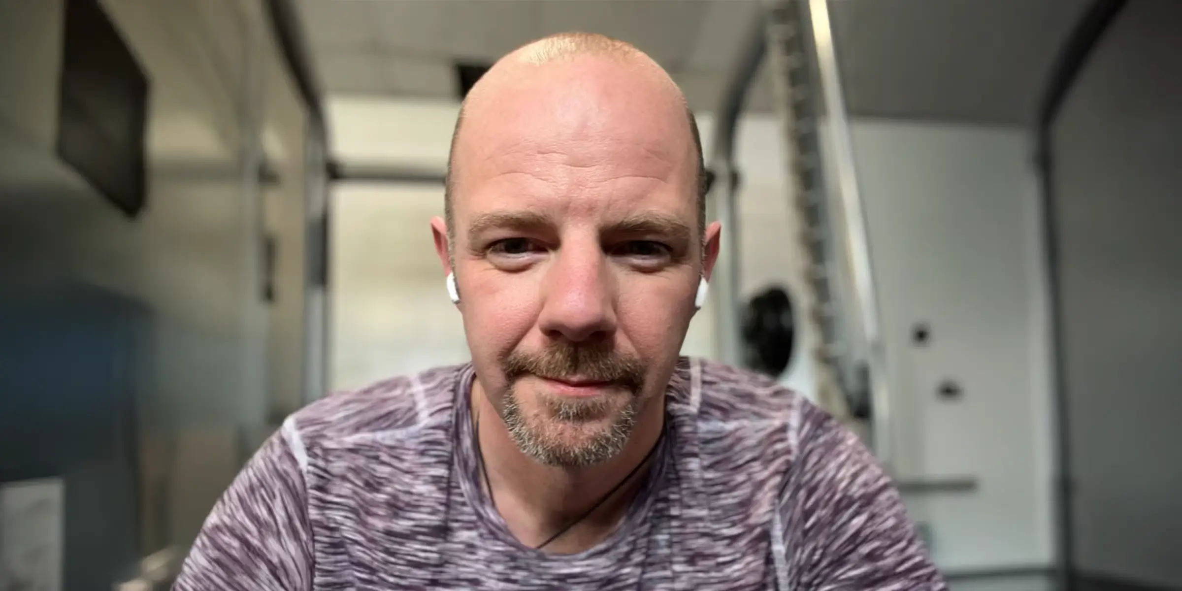 Portrait of a man at the gym wearing earphones, taken during a workout break.