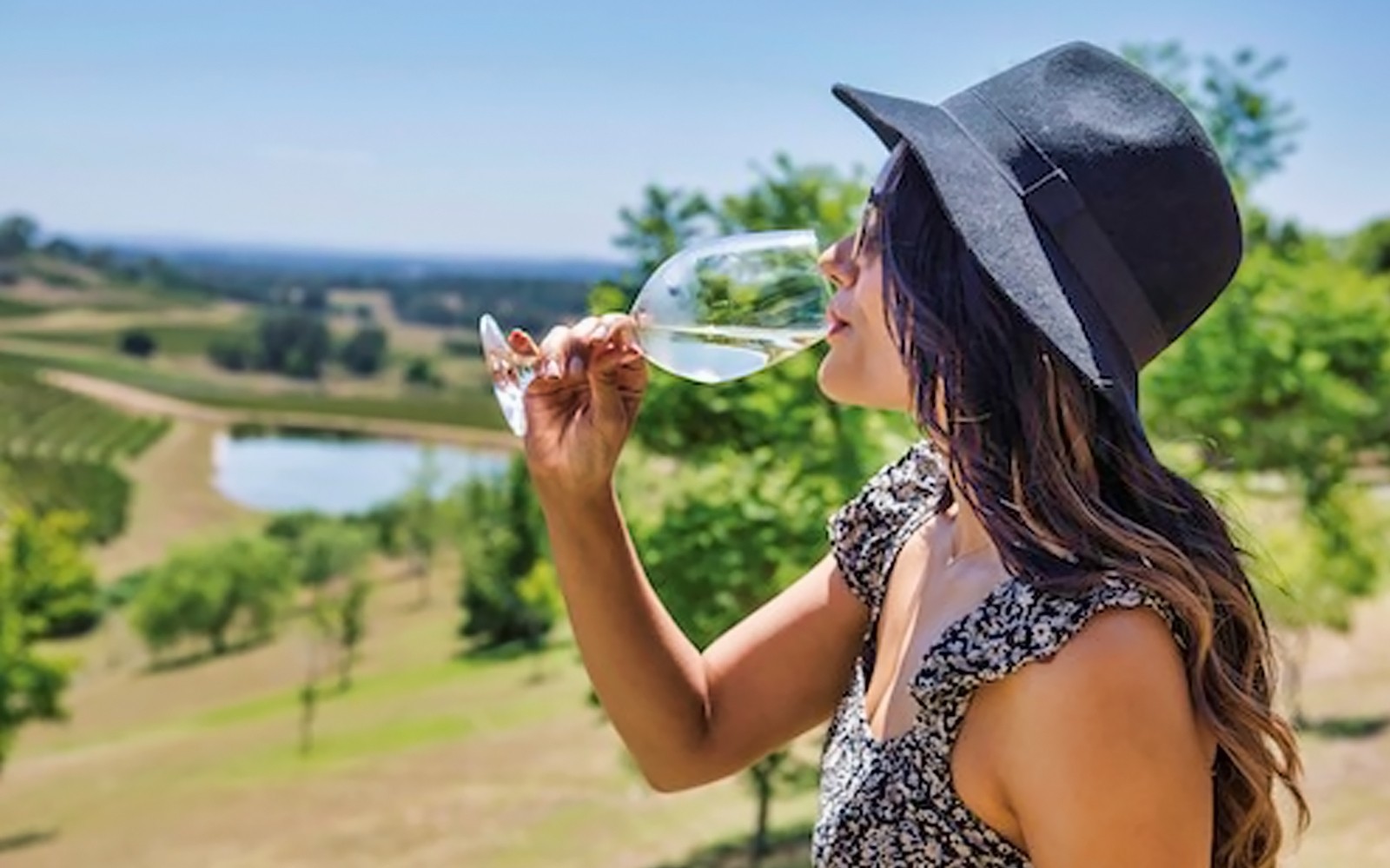 A person enjoying wine at a vineyard with scenic views.