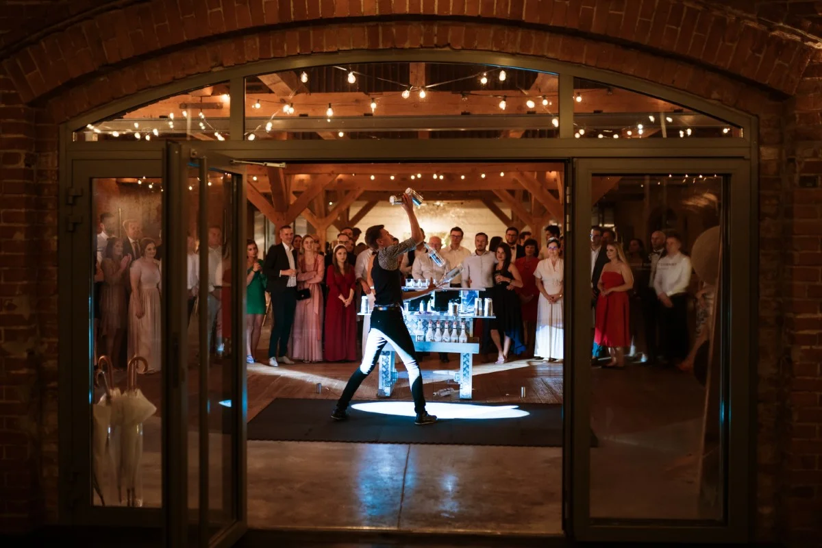 Barman na weselu pokazuje sztuczki barmańskie przed zgromadzonymi gośćmi podczas pokazu barmańskiego