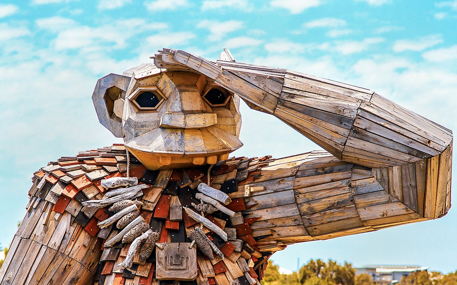 木制巨人雕塑举手致敬，属于巨人与海豚观光游船活动的一部分。