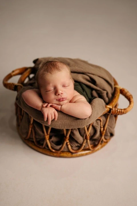 Sleeping newborn resting in a small round basket