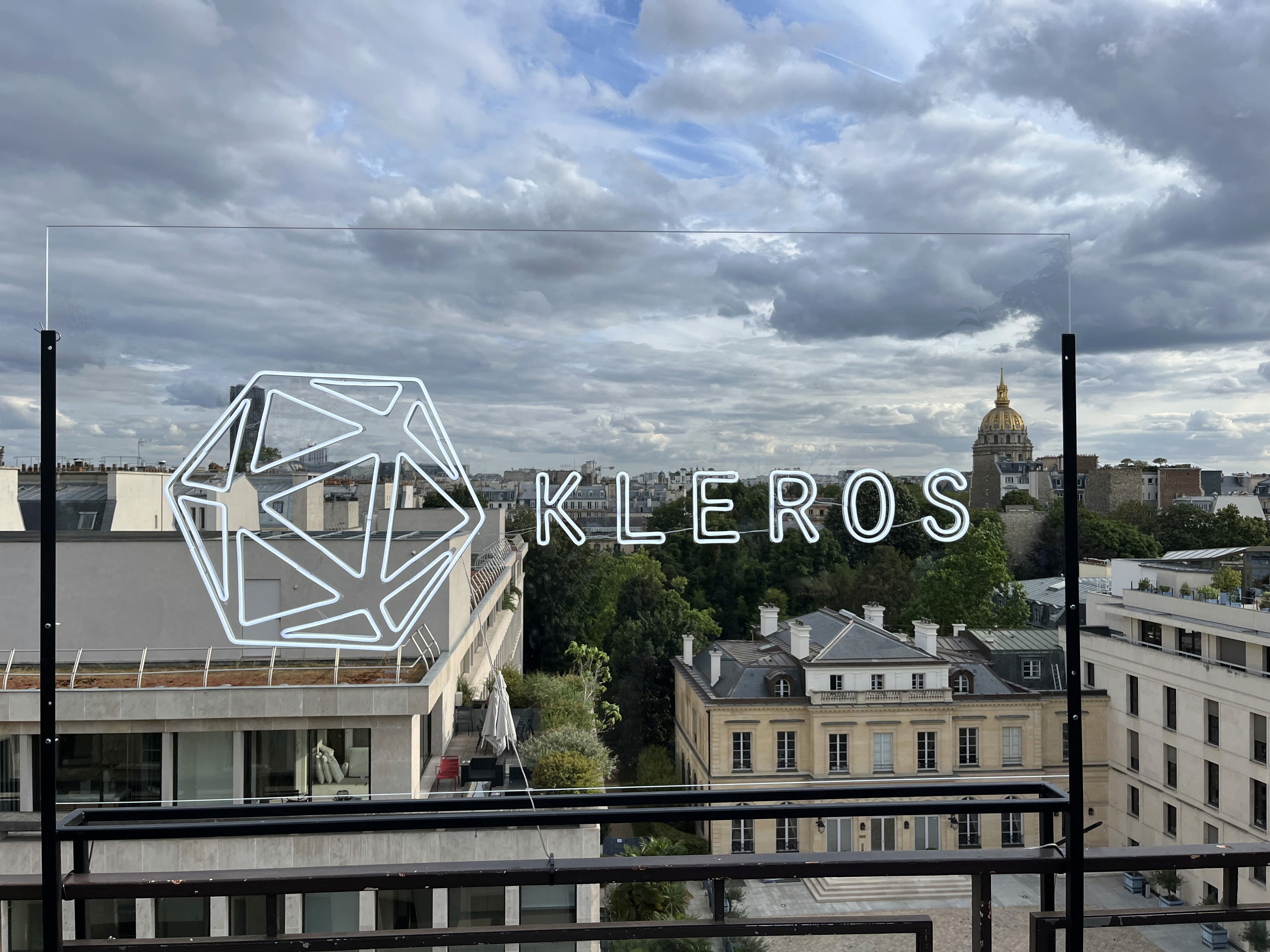 Kleros decentralized arbitration protocol logo overlaid on a European cityscape view.