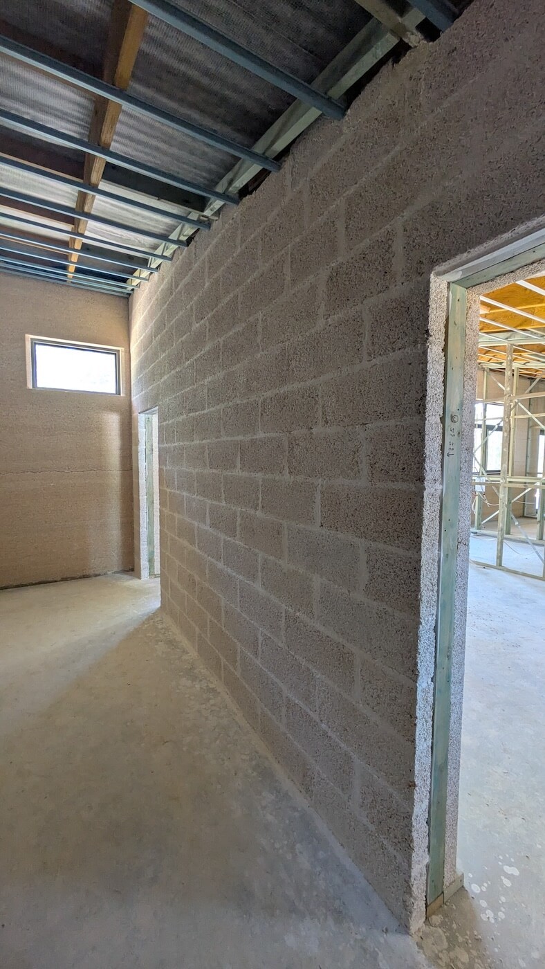 Team placing hempcrete at height beneath roof rafters during construction, highlighting the scale and labour involved in high-wall builds.