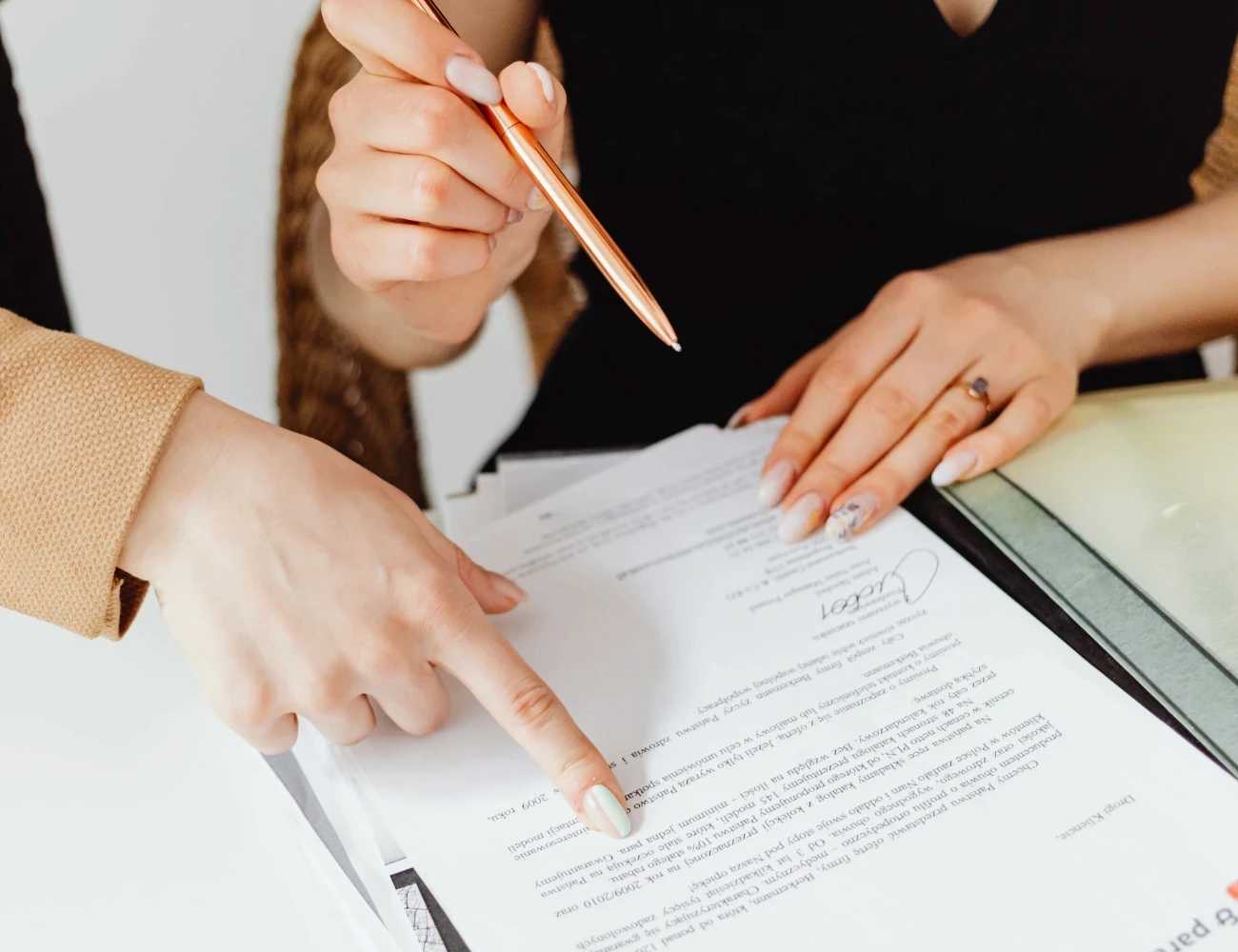 Two colleagues reviewing a signed employee handbook acknowledgement form, one pointing to a line on the page while the other holds a pen.