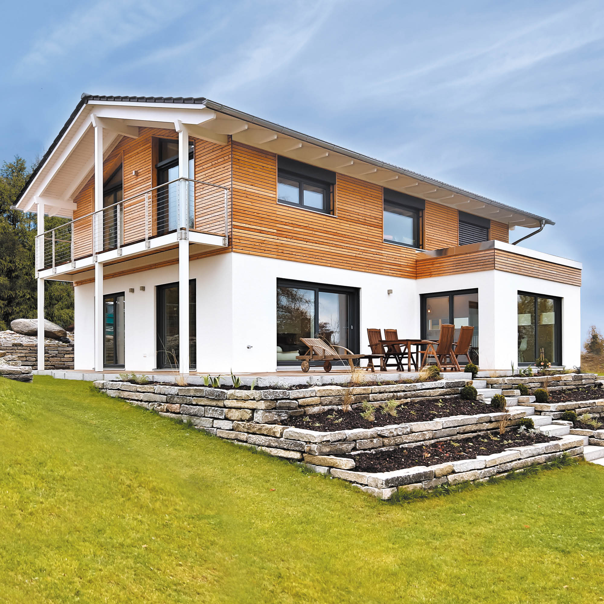 Modernes Einfamilienhaus mit Holz- und Putzfassade, Balkon, Terrasse und Terrassierung im Garten.