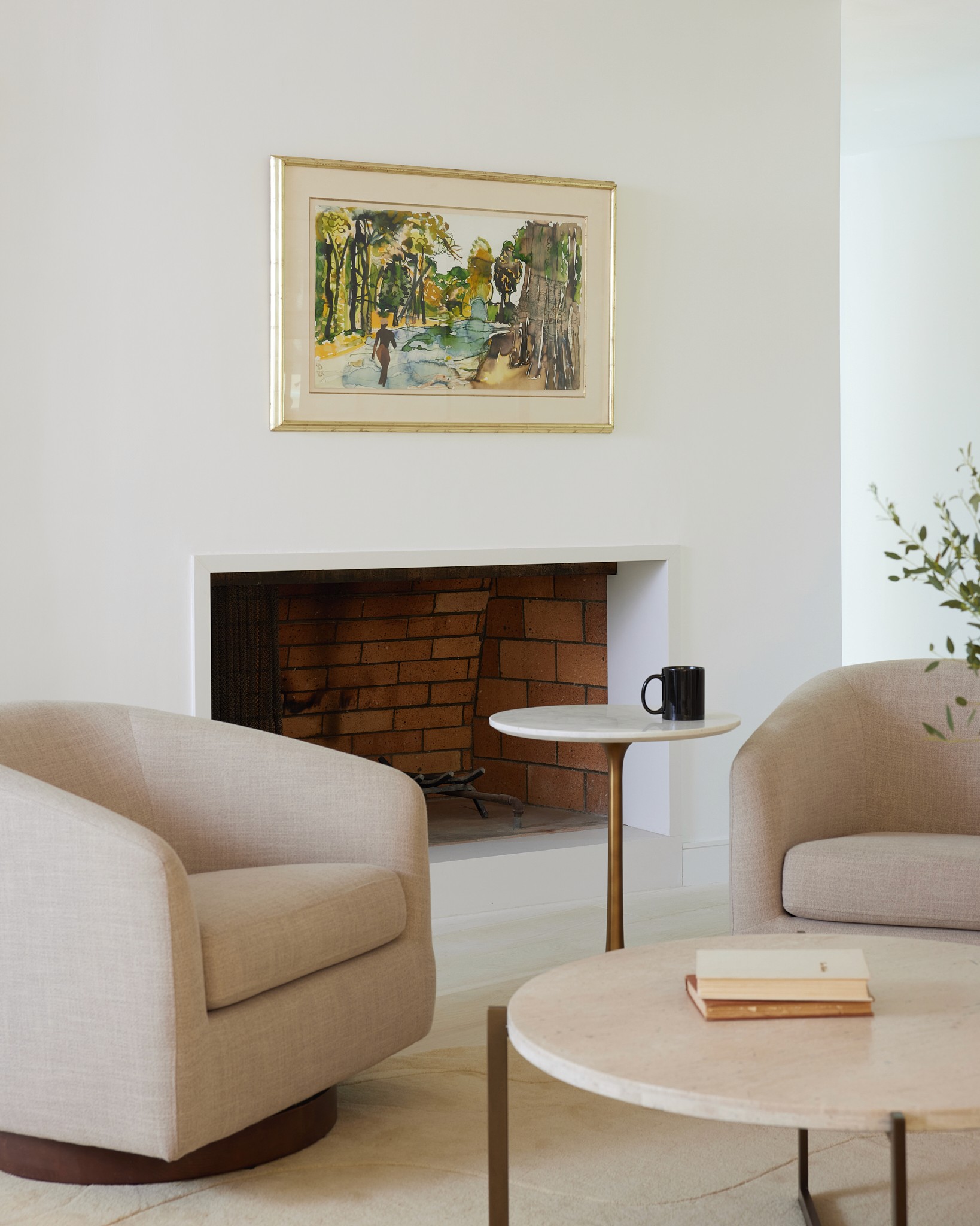 Creamy colored living room with modern chairs, side table, coffee table, a unique shaped rug, and a fireplace by Jubilee Interiors in Los Angeles, California