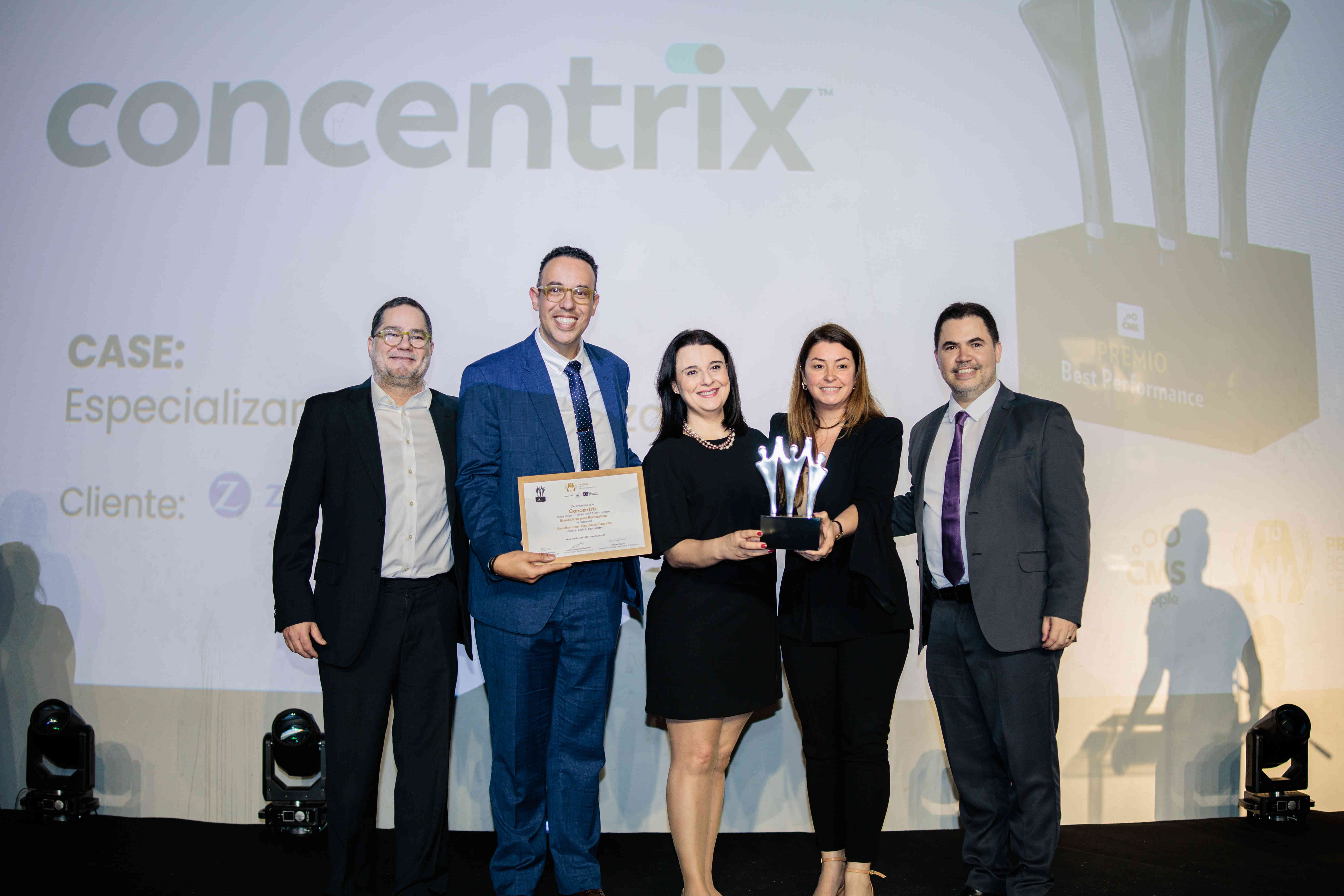 Executivos da Concentrix posando com troféu prata e certificado no palco do Prêmio Best Performance 2025