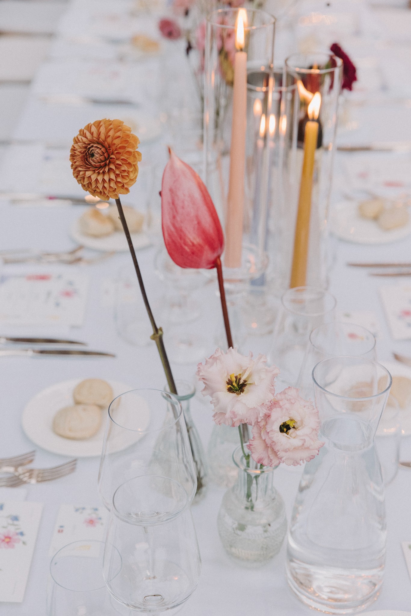 Dettagli tavolo ricevimento matrimonio con fiori rosa e dalia, candele e bicchieri al Castello di Tabiano