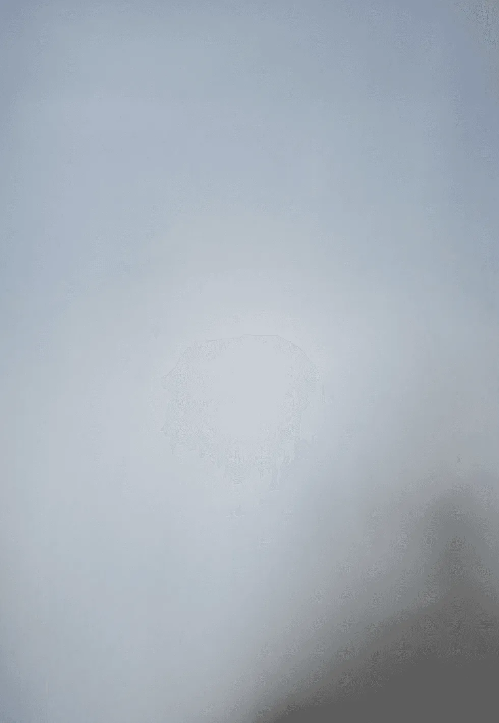 A smooth, light gray surface with a small, irregular, faded spot in the center