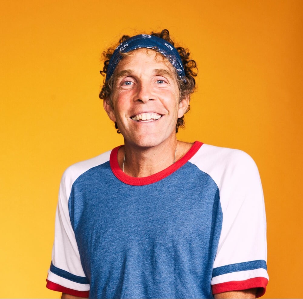 Man smiling against a bright yellow background, wearing casual clothing and a headband (no Rythm Health device visible).