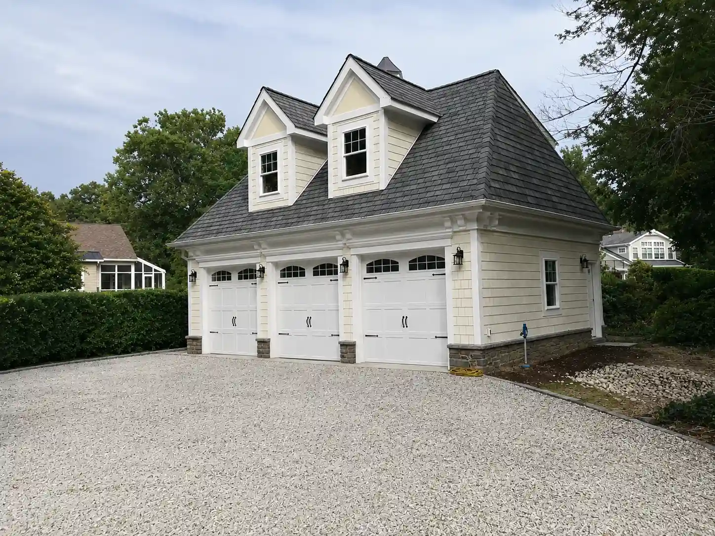 Custom three-car detached garage with dormer windows and carriage-style doors.
