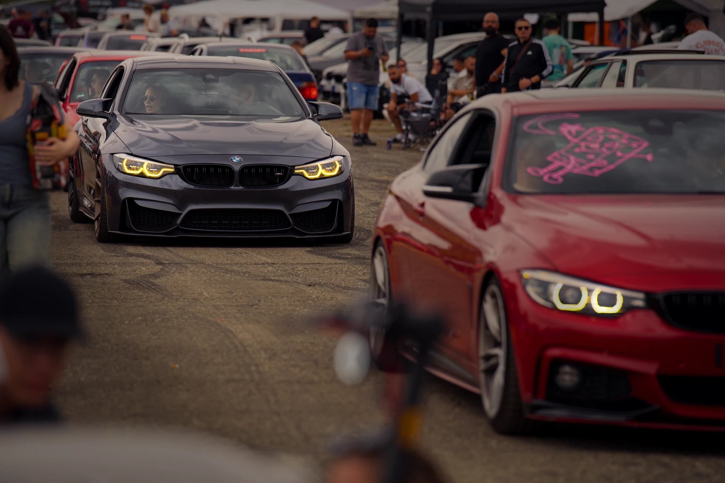Grauer BMW M4 im Autokorso auf dem BMW Syndikat Asphaltfieber 2025, umgeben von Besuchern, Fahrzeugen und Festivalstimmung.