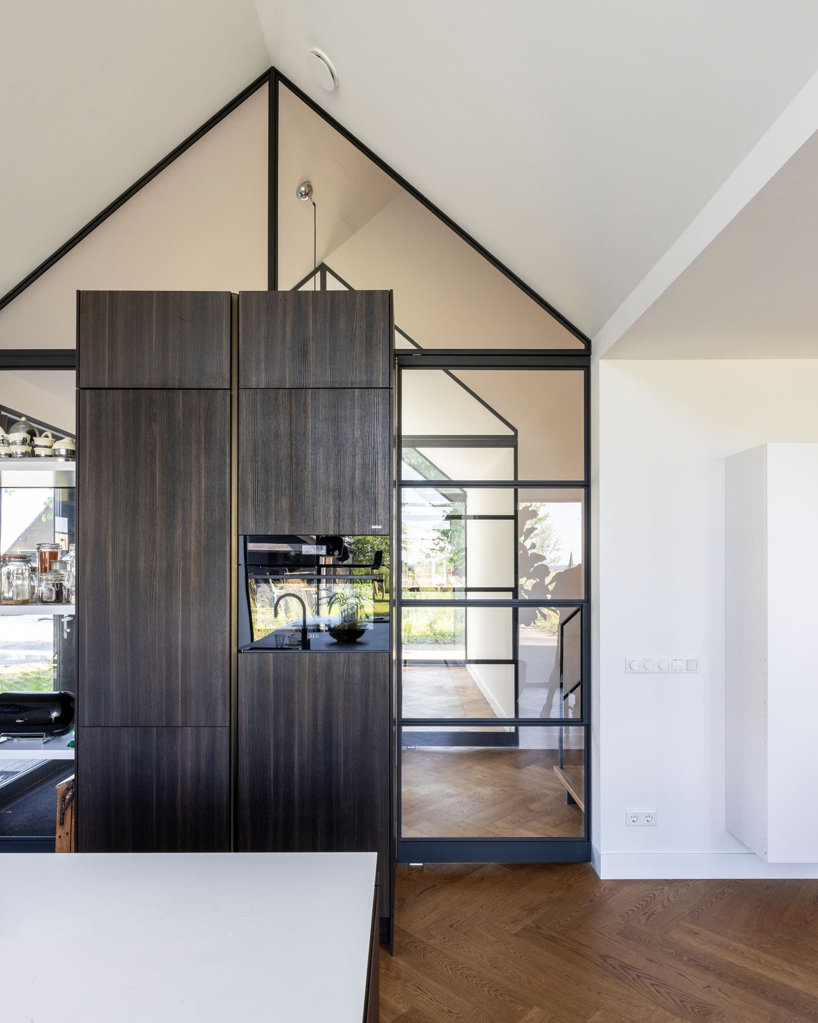 Moderne keuken met wit kookeiland, houten kastenwand en donkere vloer