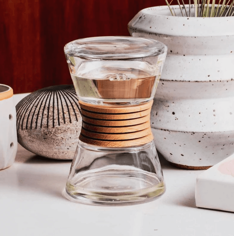 Hour-shaped glass bottle with wooden diffuser in the middle.