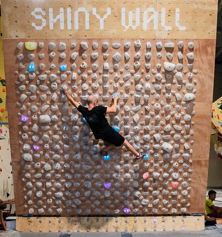 Bouldern an der Shiny Wall Systemwand mit hunderten Griffen und leuchtenden Routenmarkierungen – Indoor Bouldern mit variabler Schwierigkeit im The Boulder Room München.