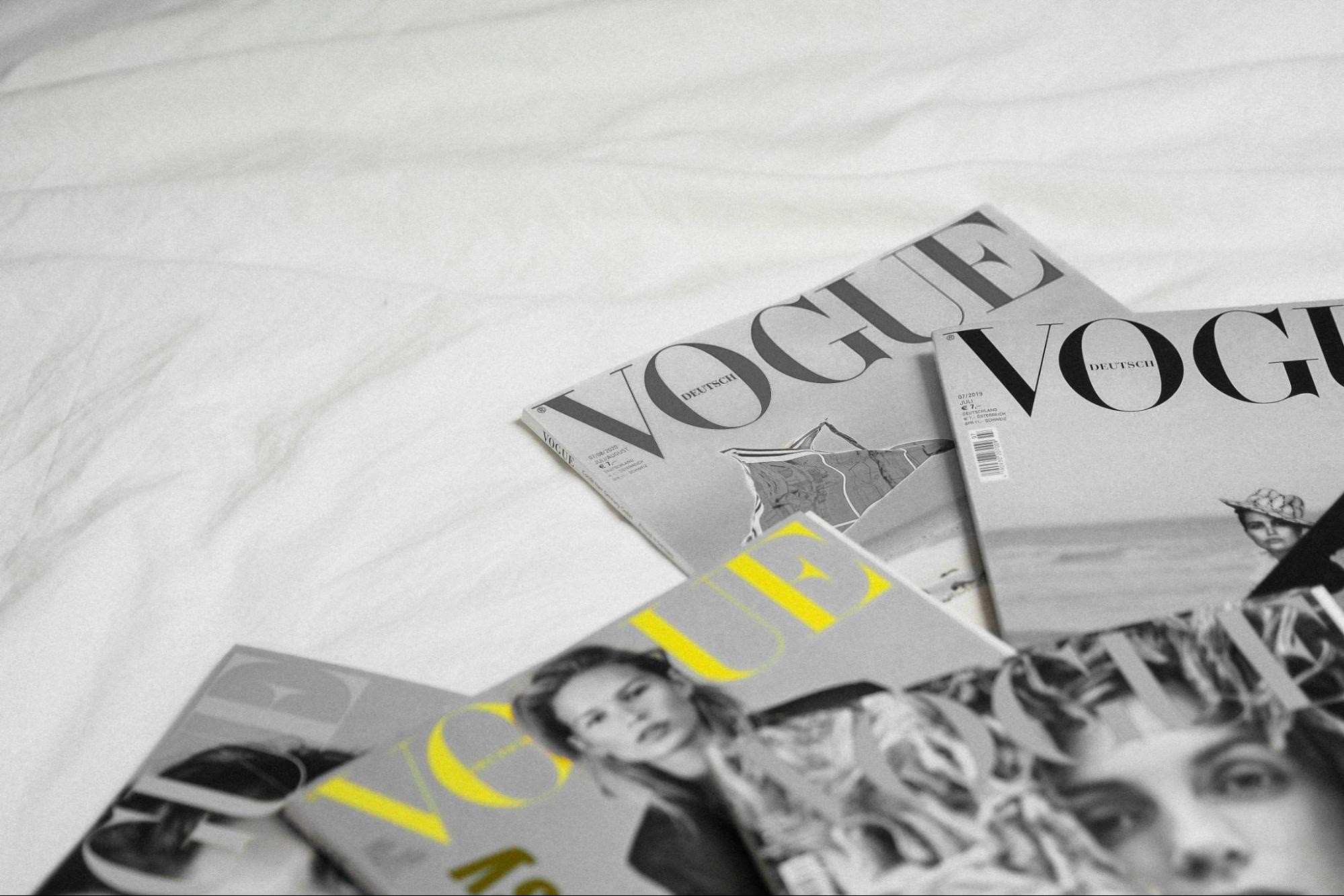 several vogue magazines spread across a bed