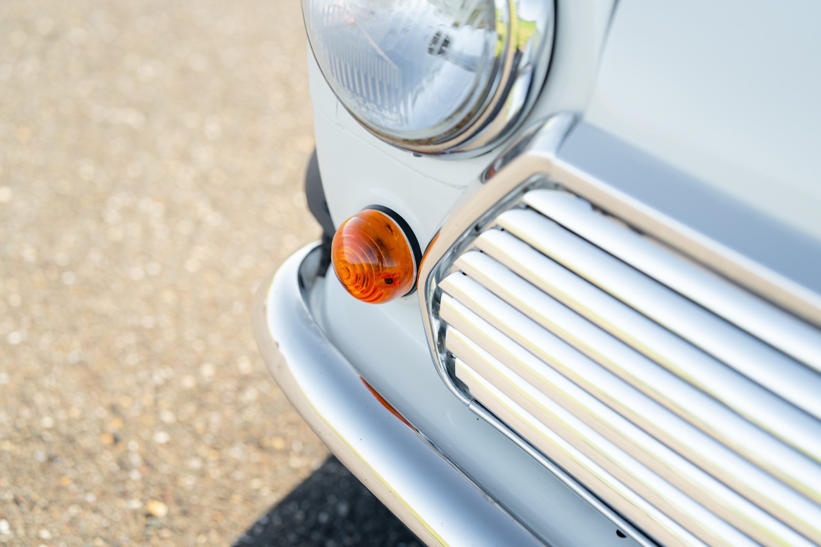 Close-up of a vintage car's front, highlighting a chrome grille and an orange turn signal.