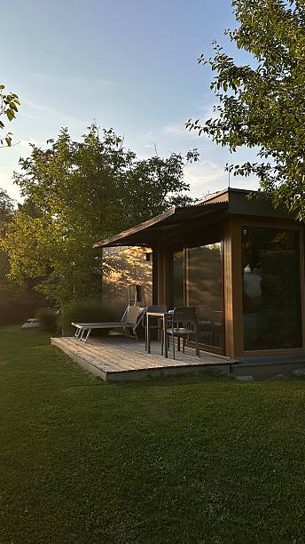 Modern houten tuinkantoor met glazen gevel in groene tuin tijdens zonsondergang in Groningen