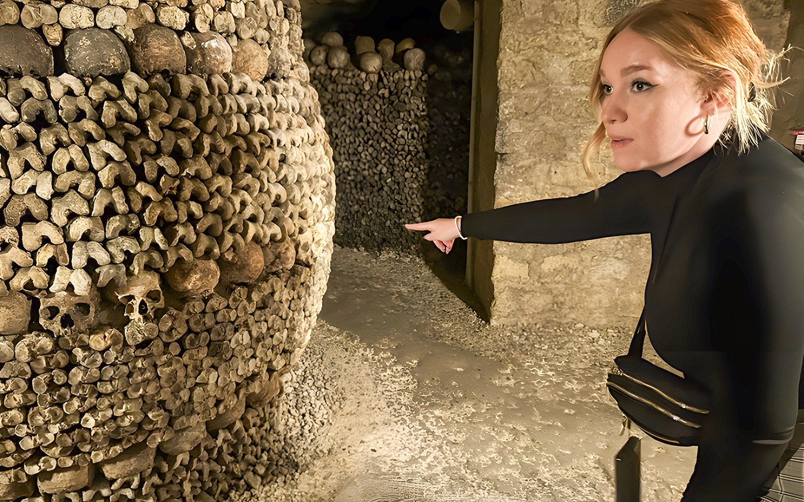 导游在巴黎地下墓穴的小团体游中指着头骨和骨骼。