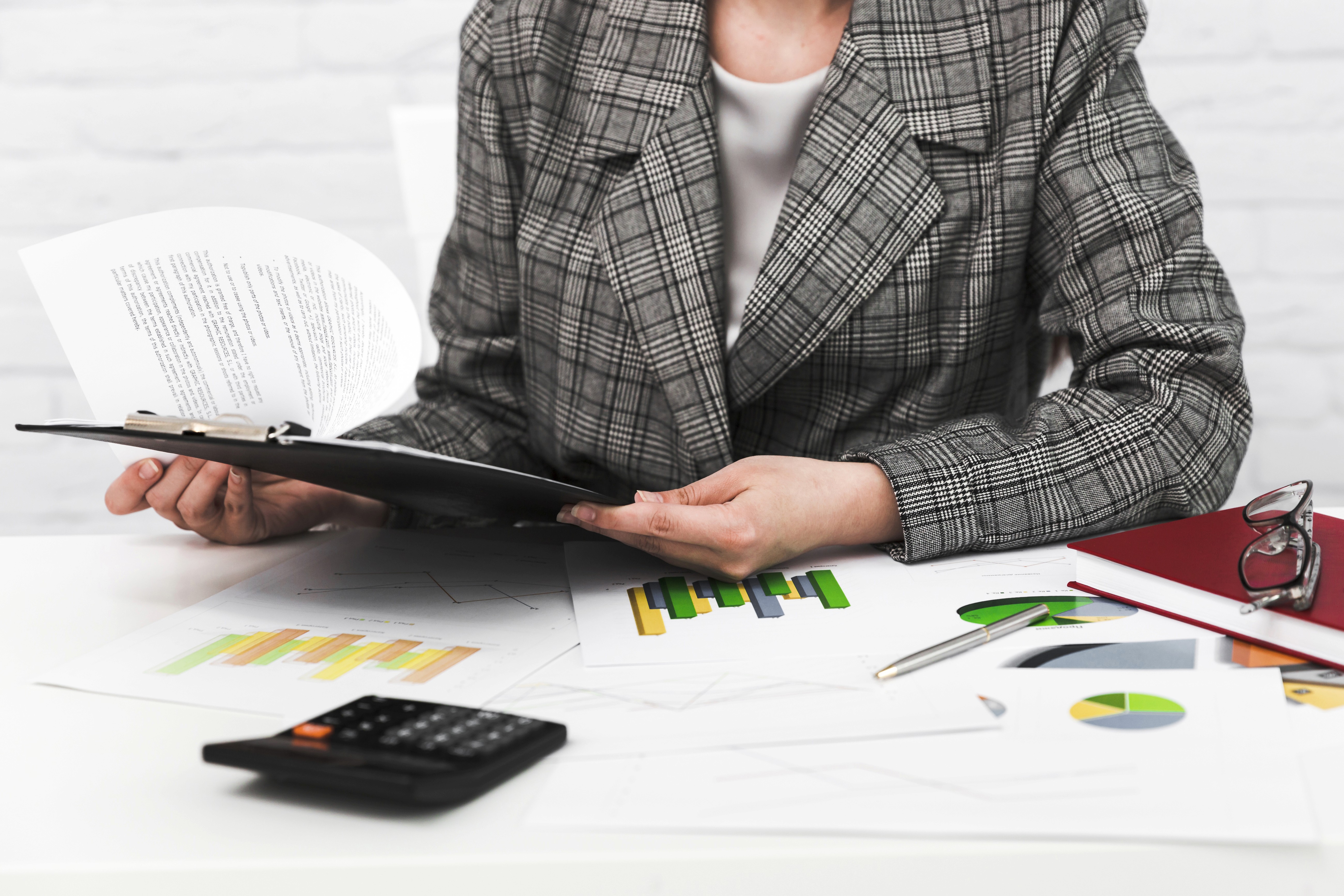 woman signing on white printer paper beside woman about to touch the documents