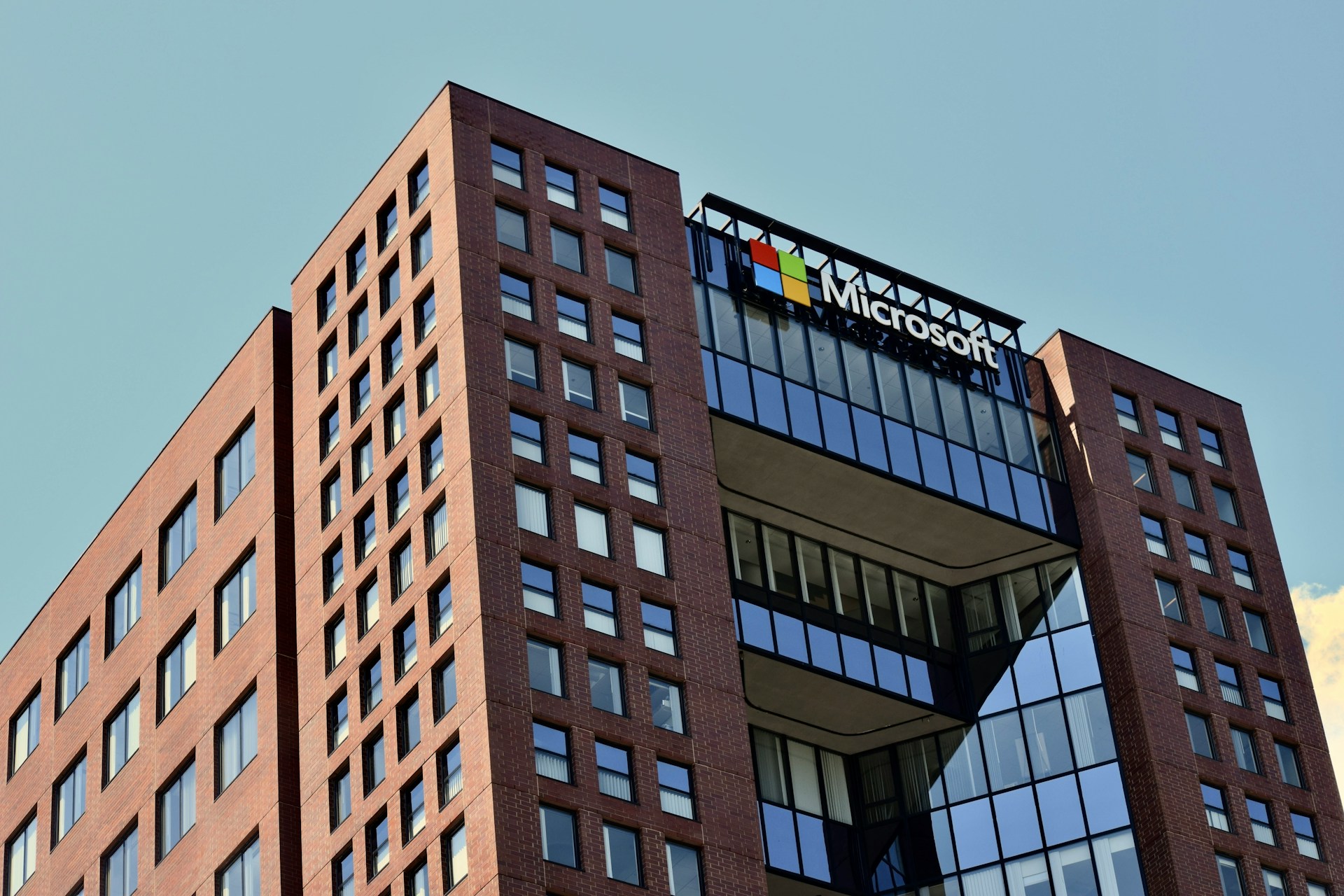 Exterior view of a red brick office building with the Microsoft logo and colorful flag icon displayed on the upper facade.