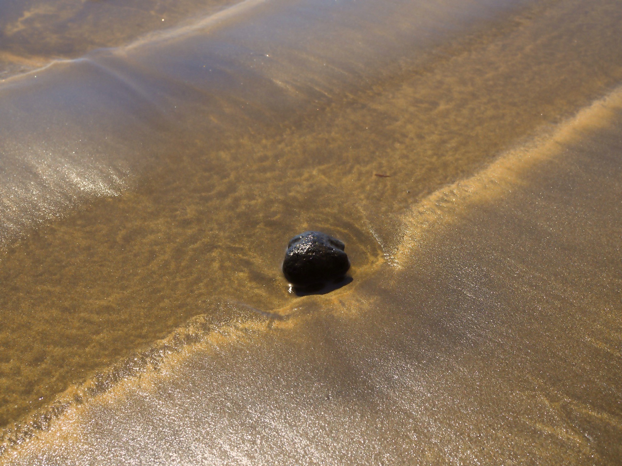 Sand,Meer und ein schwarzer Stein