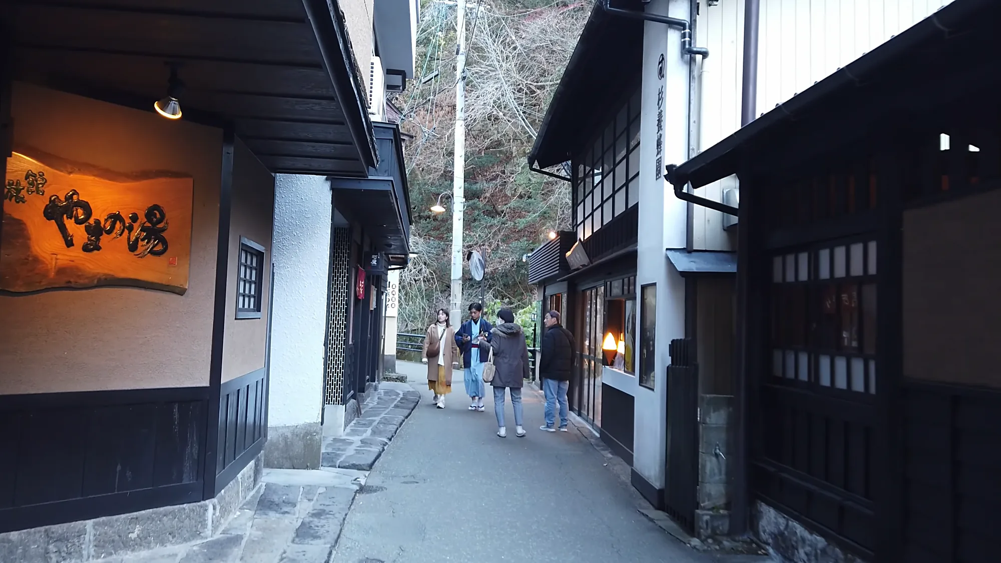 People seated at a footbath on a Kurokawa Onsen lane in low sun