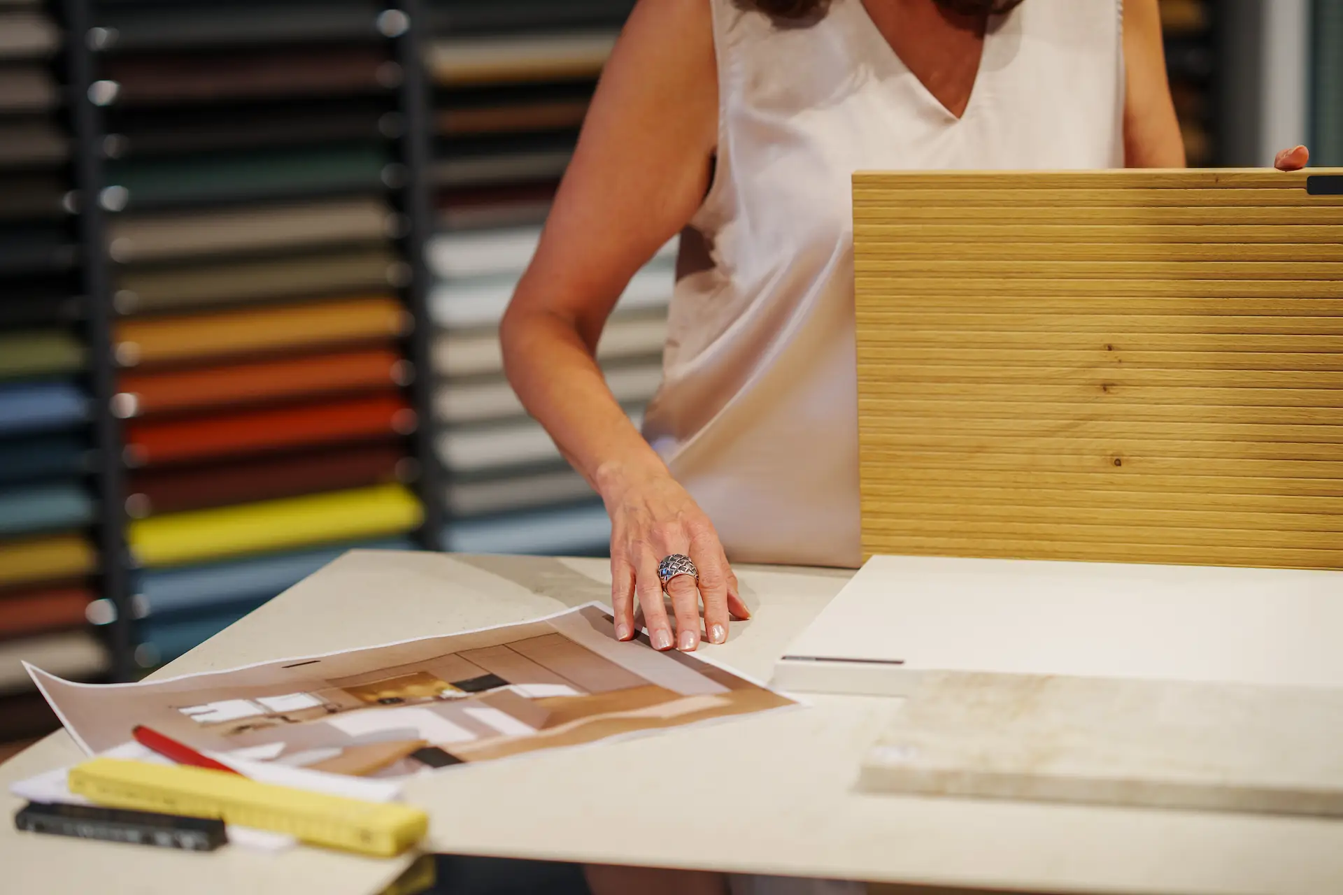 Claudia Winiger an einem Arbeitstisch mit Materialmustern, Holzlamellen und Einrichtungsplänen.
