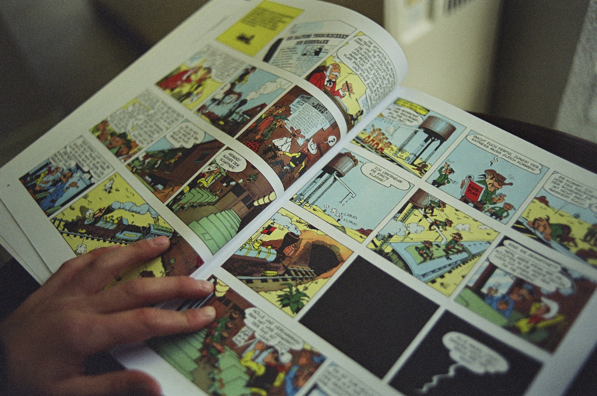 A hand holding open a colorful comic book