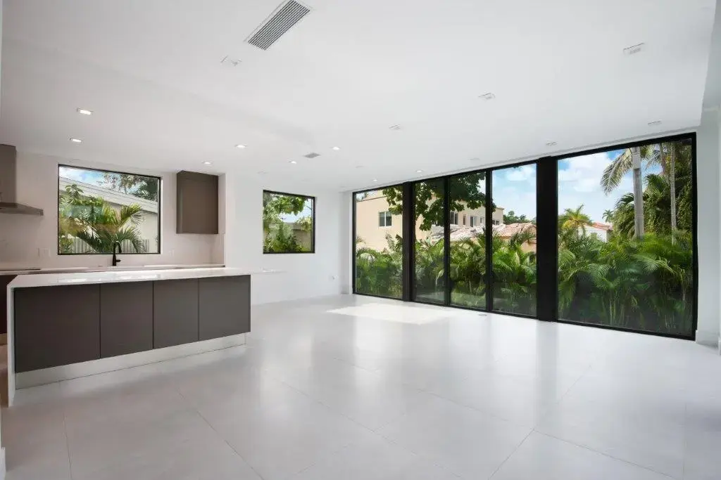Open plan kitchen and living area with floor-to-ceiling glass in modern Miami Beach residence by Atelier International LLC