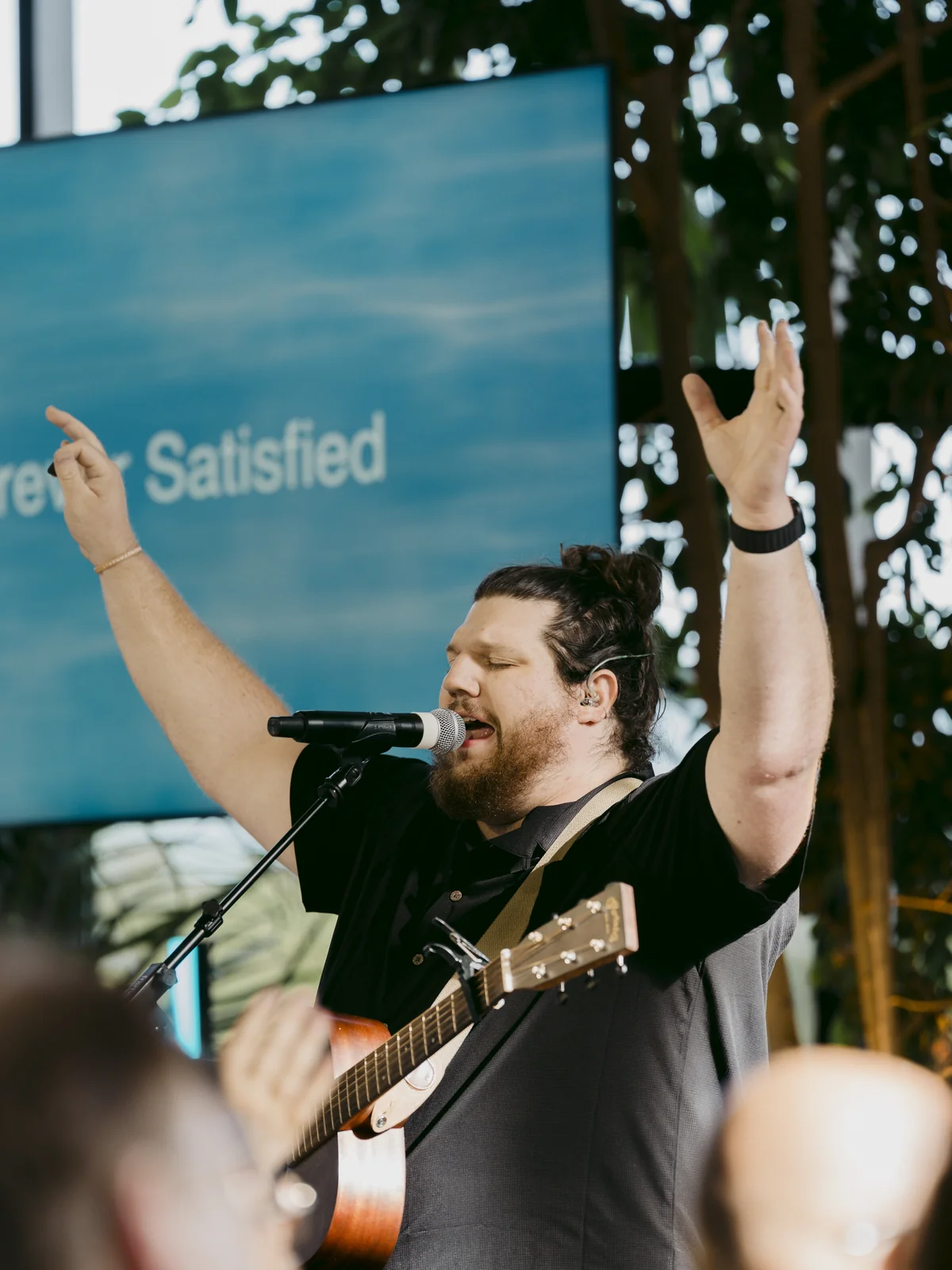 Worship leader with guitar and arms raised leading worship at Elan Church in Naperville