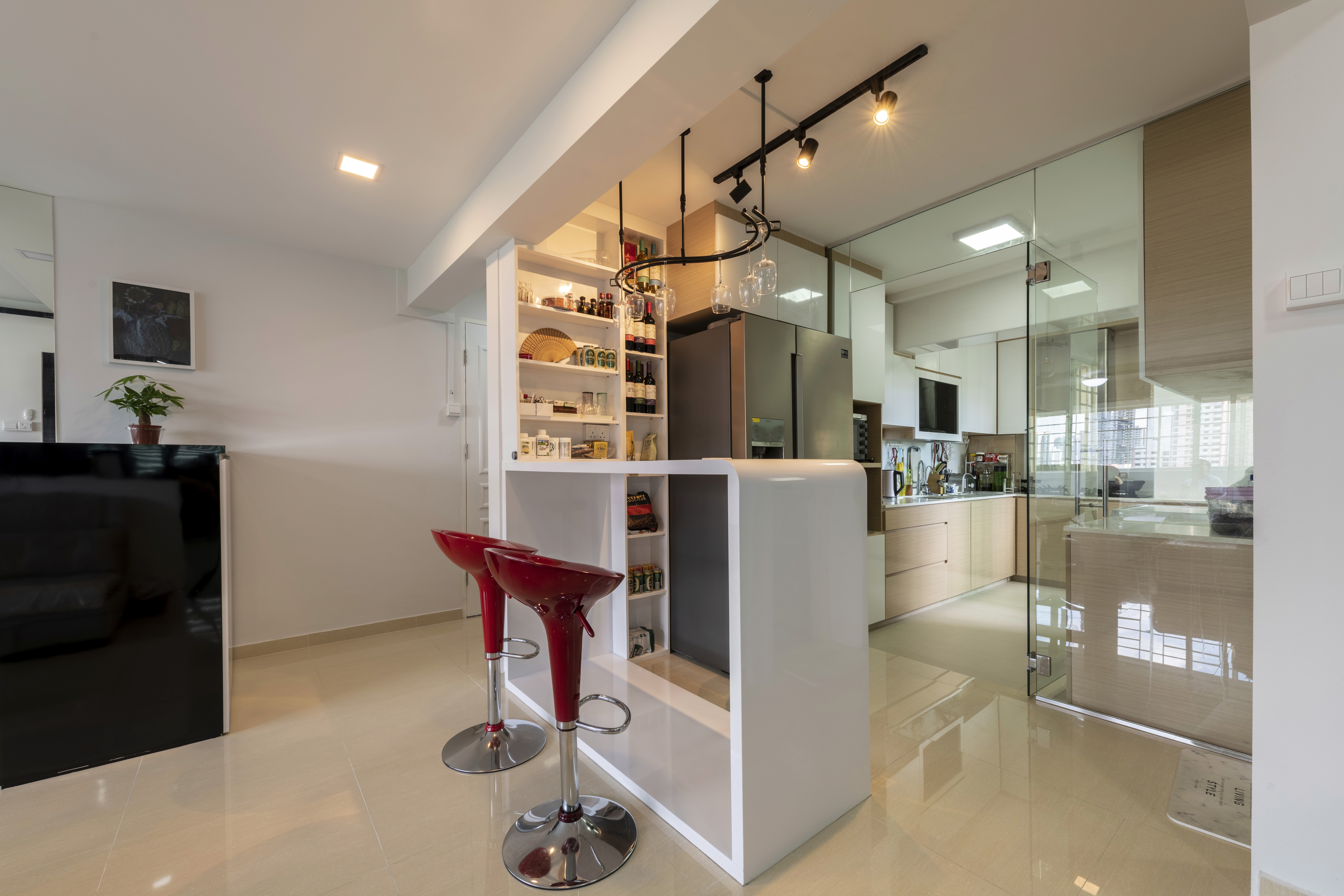 Kitchen and bar area with glass partitions, a streamlined counter, and open shelving, maximizing light and connectivity while keeping zones distinct.