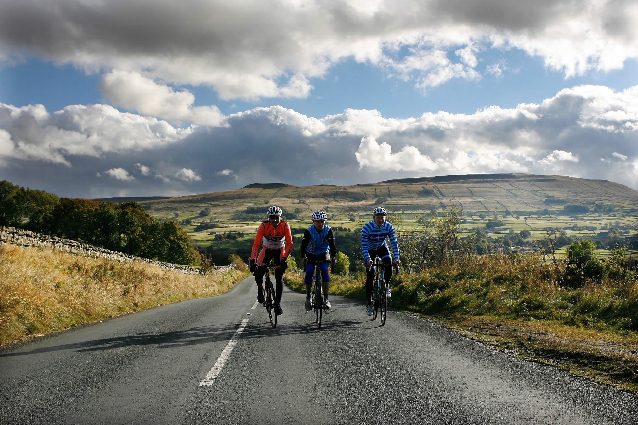 Cyclists riding through rolling hills under a sunny sky