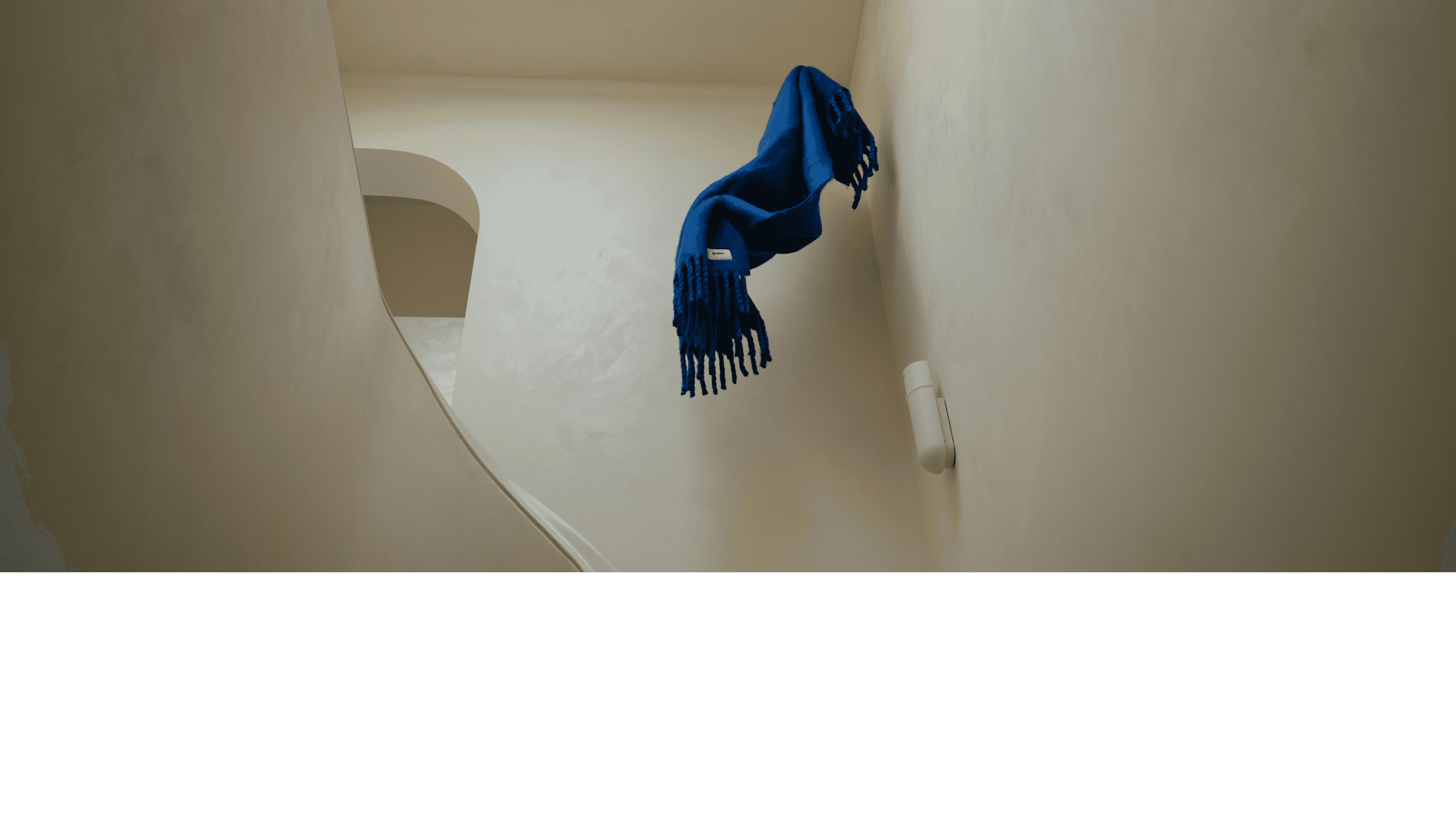 A cozy scene showing a person dressed in white lounging on a sofa, surrounded by plush blankets in cream and deep teal. Both blankets feature the "NORMY" label, highlighting the brand, and add a touch of comfort and style to the setting, which also features colorful tile flooring.