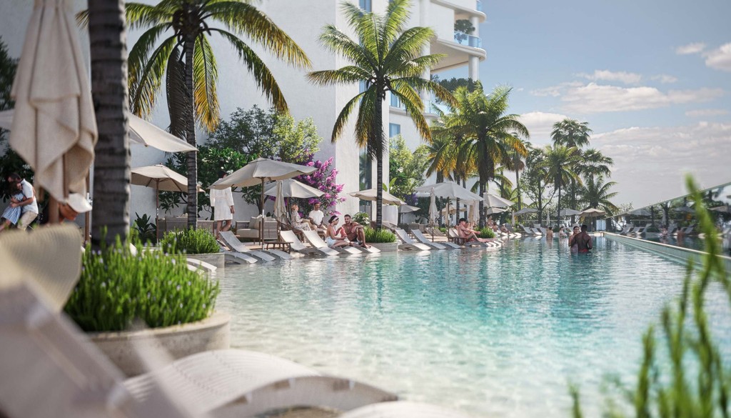 A serene pool with lounge chairs and umbrellas, set against the backdrop of a beach and azure Lapis waters.
