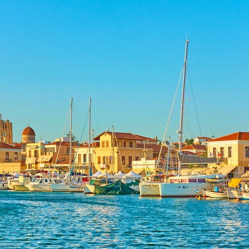 晴朗的蓝天下，船只停泊在港湾，背景是沿海小镇和建筑物。